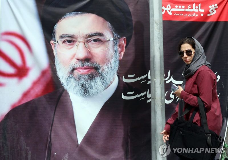 이란 최고지도자 초상화 앞 지나는 이란 여성 (출처=연합뉴스)