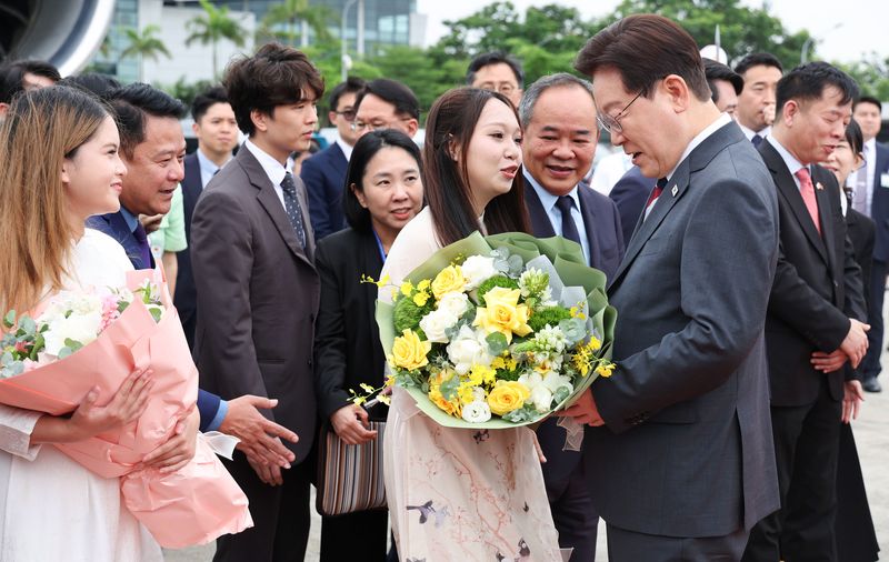 베트남 국빈 방문 일정을 마친 이재명 대통령이 24일(현지 시간) 베트남 하노이 노이바이 국제공항에서 환송 인사들과 인사하며 꽃다발을 받고 있다. 뉴시스