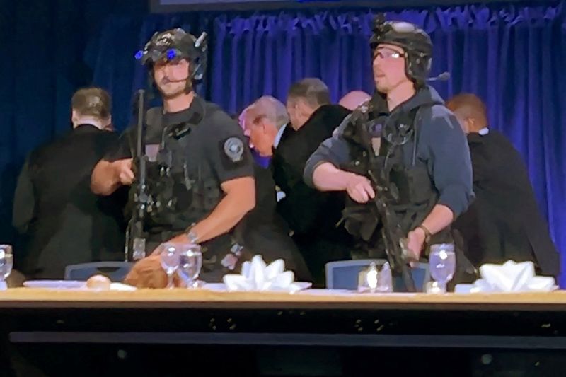 25일(현지시간) 미국 워싱턴DC 워싱턴 힐튼 호텔에서 백악관출입기자협회(WHCA) 만찬 행사에 참석했던 도널드 트럼프 미국 대통령(가운데)이 총격 이후 피신하고 있다.로이터연합뉴스