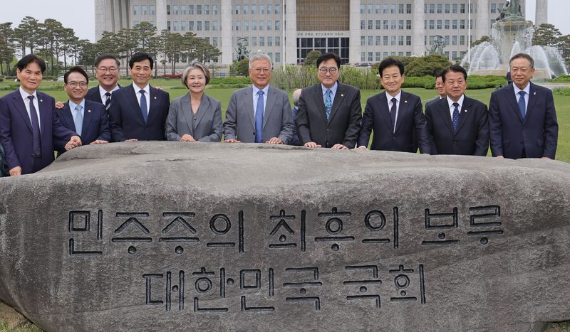 우원식 국회의장이 27일 서울 여의도 국회에서 4.27 판문점선언 8주년 기념식에 참석한 문재인 전 대통령 내외를 비롯한 참석자들에게 ‘민주주의 최후의 보루 대한민국 국회’ 문구가 새겨진 상징석 앞에서 기념촬영을 하고 있다. 뉴스1