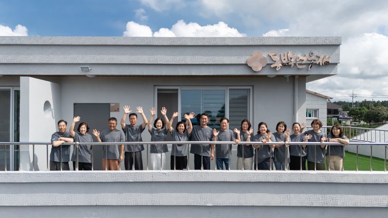 서귀포시 남원읍 신흥2리 동백마을 주민들이 마을 체류 공간 앞에서 손을 흔들고 있다. 신흥2리 동백마을은 2023년 유엔 세계관광기구가 인증한 최우수 관광마을로 주민 공동체와 환대의 가치를 이어가고 있다. /사진=제주관광공사 제공