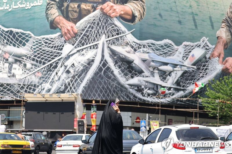 이란 테헤란 거리에 걸린 선전화 앞을 지나는 여성의 모습 (출처=연합뉴스)