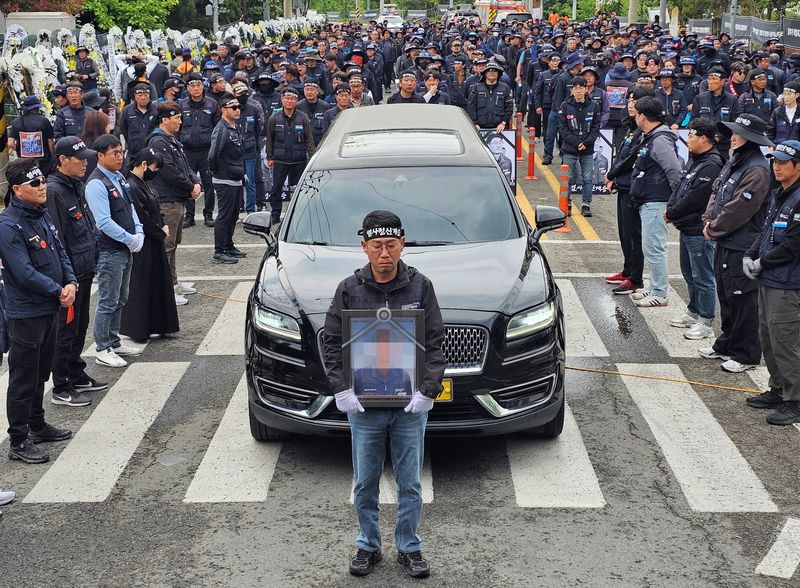 김동국 민주노총 화물연대 위원장이 1일 숨진 조합원 A 씨 추모제에서 A 씨 영정 사진을 운구차 앞에서 들고 있다. 2026.5.1/뉴스1 한송학기자