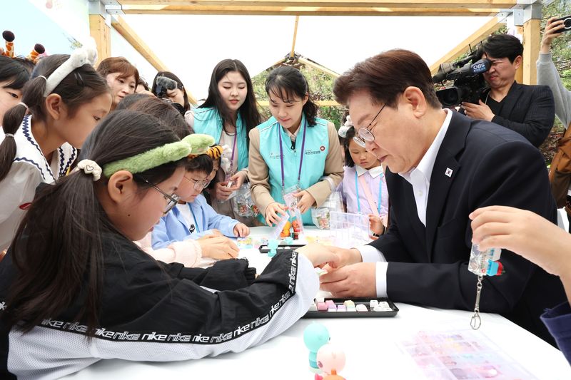 이재명 대통령이 5일 청와대 녹지원에서 열린 2026 어린이날 초청행사에 참석한 어린이들과 나만의 키캡 만들기 체험을 하고 있다. 뉴스1