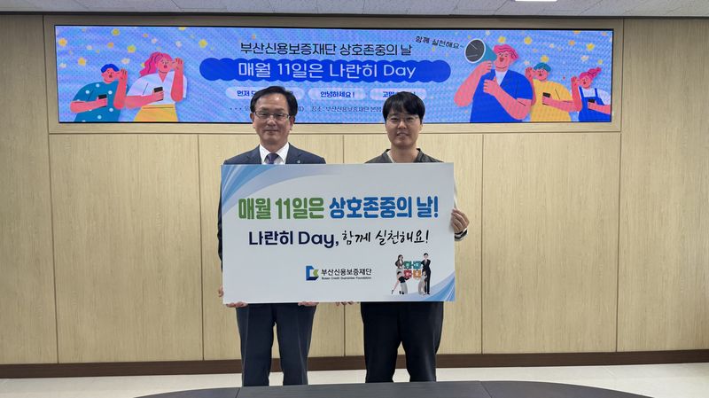 부산신용보증재단 구교성 이사장(왼쪽)이 나란히 데이 캠페인 홍보 기념사진을 촬영하고 있다. 부산신용보증재단 제공