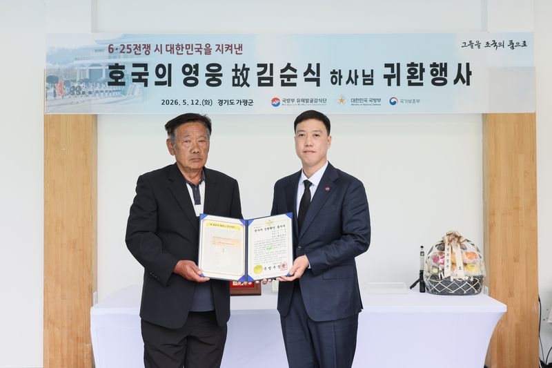 12일 오전에 열린 '故 김순식 하사 호국의 영웅 귀환 행사'에서 김성환 국방부 유해발굴감식단장 직무대리(육군 중령, 오른쪽)가 고 김순식 하사의 아들 김의영 씨(왼쪽, 72세)에게 전사자 신원확인 통지서를 전달하고 있다. 국방부 제공