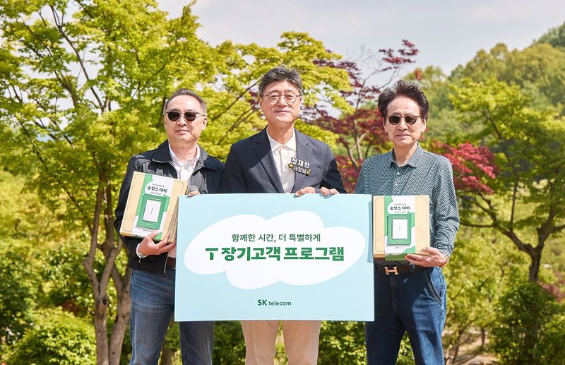 정재헌 SKT CEO(가운데)가 SKT와 40년 이상 함께한 고객 김홍재씨(왼쪽)와 고지홍씨에게 선물세트를 전달하고 기념촬영하고있다. SKT 제공