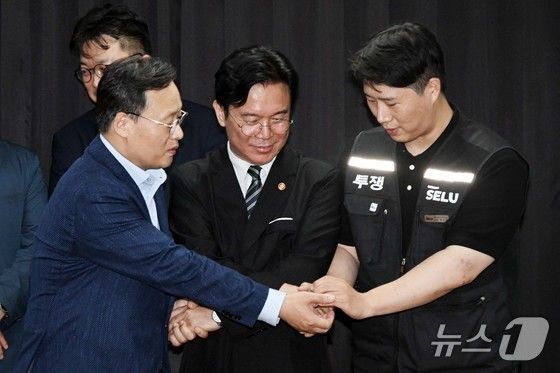 20일 경기도 수원시 장안구 경기고용노동청에서 열린 삼성전자 임금협상을 마친 후 여명구 삼성전자 반도체(DS) 피플팀장(왼쪽부터)과 김영훈 고용노동부 장관, 최승호 삼성그룹 초기업노동조합 삼성전자지부 위원장이 잠정 합의한에 서명한 후 손을 맞잡고 있다. (공동취재) 2026.5.20/뉴스1