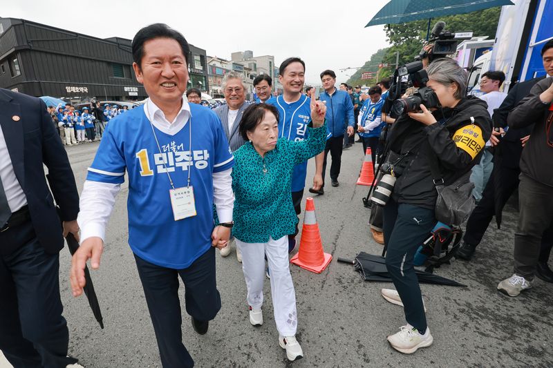 더불어민주당 정청래 총괄상임선거대책위원장이 21일 충남 공주산성시장에서 민주당 박수현 충남도지사 후보와 김영빈 충남 공주부여청양 국회의원 보궐선거 후보 지원 유세를 하는 가운데 배우 전원주 씨 손을 잡고 이동하고 있다. /사진=연합뉴스