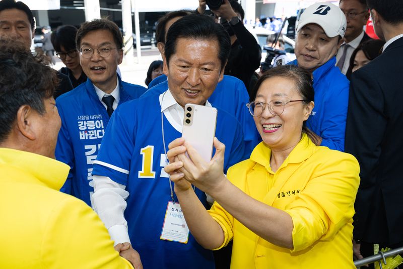 우상호 강원특별자치도지사 후보와 김중남 강릉시장 후보 지원유세에 나선 정청래 더불어민주당 대표가 22일 강원 강릉시 주문진 시장에서 상인과 기념 촬영을 하고 있다. 2026.5.22 ⓒ 뉴스1 유승관 기자