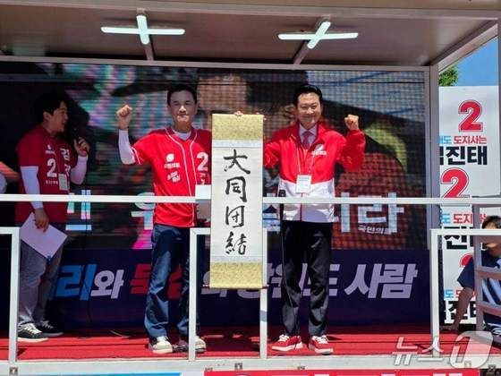 장동혁 국민의힘 대표와 김진태 강원도지사 후보가 30일 오전 강원 춘천 공지천사거리 앞에서 '대동단결(大同團結)' 붓글씨 퍼포먼스를 한 뒤 유세차에 올라 족자를 들고 강원도지사 선거 승리를 다짐하고 있다.(김진태 캠프 후보 측 제공, 재판매 및 DB금지)