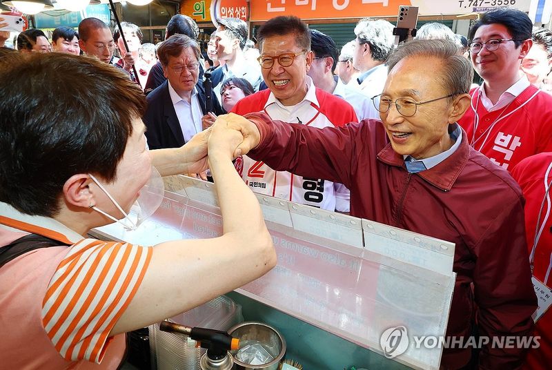 상인과 인사하는 이명박 전 대통령 (출처=연합뉴스)