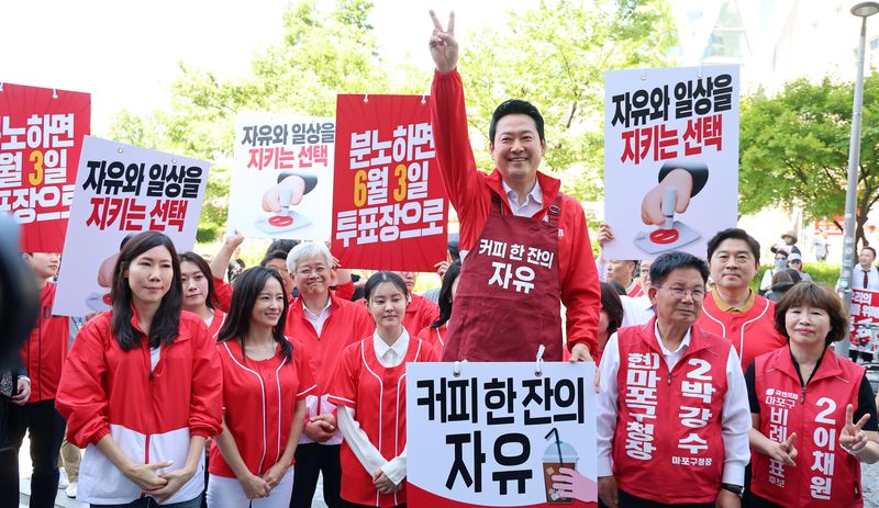 국민의힘 상임선거대책위원장인 장동혁 대표(가운데)가 31일 서울 홍대입구역에서 '커피 한 잔의 자유'라는 문구가 적힌 앞치마를 입고, 'V'자 사인을 보내면서 오는 3일 지방선거에서 대국민 투표 참여를 호소하고 있다. 연합뉴스