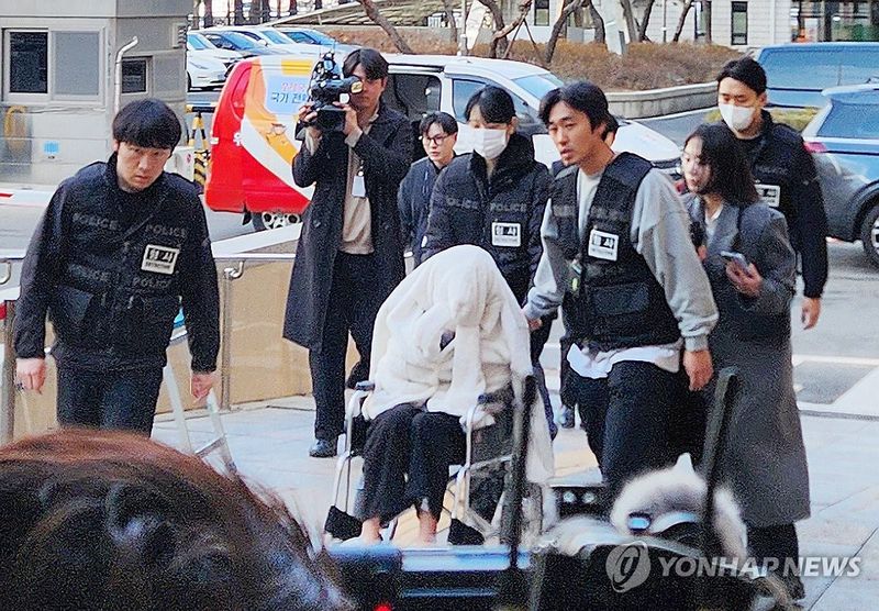 약에 취한 상태로 외제 SUV 차량을 몰고 반포대교를 달리다 한강 둔치로 추락한 운전자 A씨가 지난 2월 27일 서울 마포구 서부지방법원에서 열린 구속 전 피의자 심문(영장실질심사)에 옷으로 얼굴을 가리고 휠체어를 탄 채 출석하고 있다. 연합뉴스