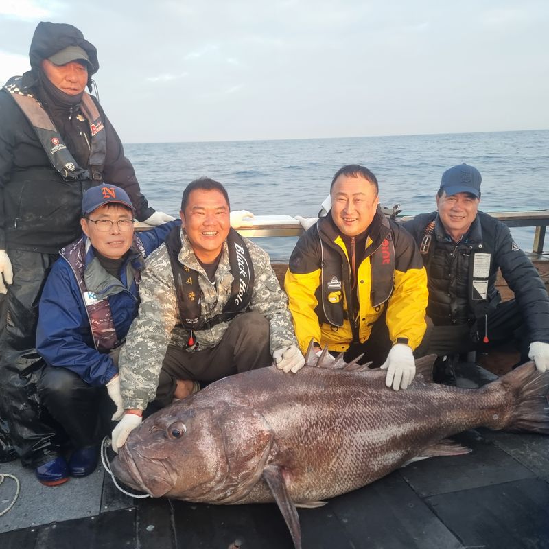 지난 1일 부산 해상에서 집념과 사투 끝에 낚아 엉청난 크기의 돗돔 뒤에서 부산용호어촌계 김광효 선장(앞줄 왼쪽 두번째) 등 함께 승선한 일행들이 기념촬영을 하고 있다. 온닥터TV 제공