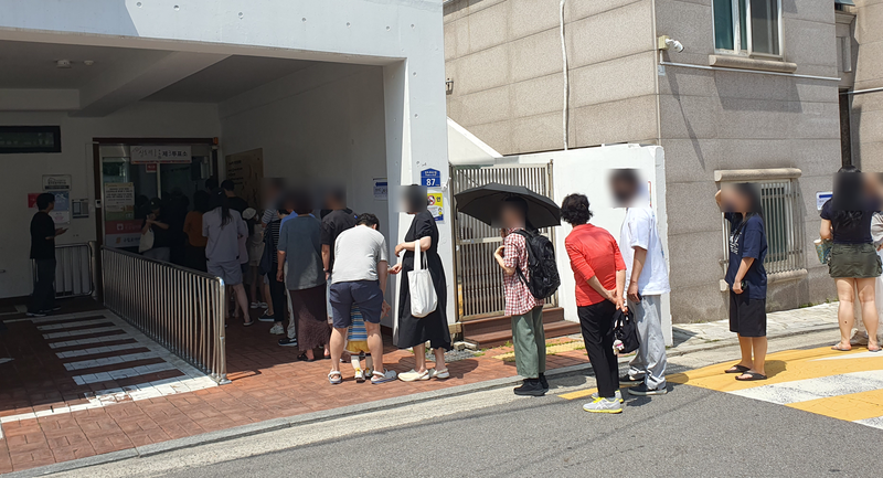 서울 동작구 로야어린이집에 마련된 상도제1동 제3투표소 앞에서 유권자들이 줄을 서서 순서를 기다리고 있다. 그늘이 없는 도로까지 대기줄이 이어지자 주민들은 양산과 손풍기를 꺼내들어 더위를 피했다. 사진=최승한 기자