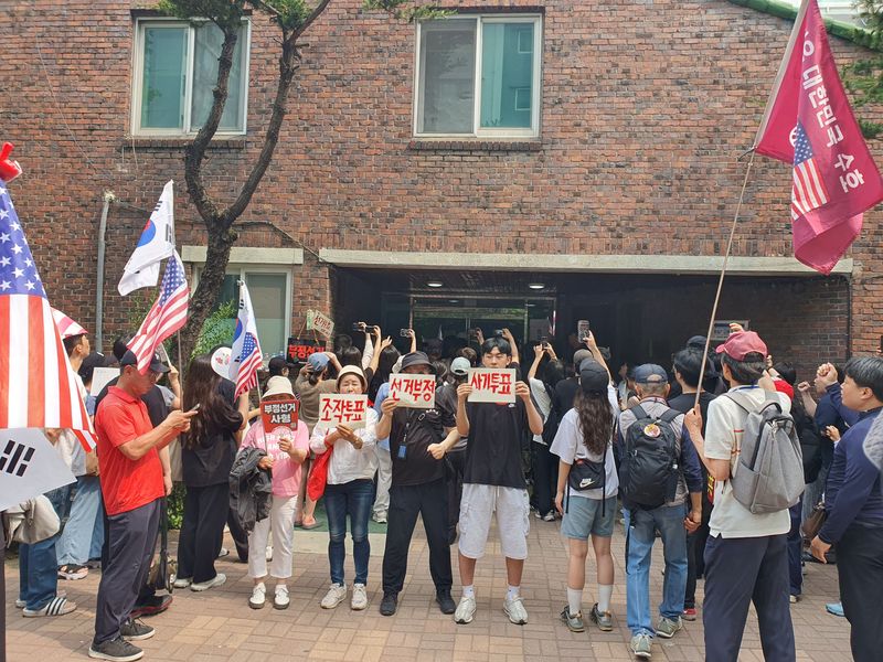 6·3 지방선거 투표용지 부족 사태가 발생한 서울 송파구 잠실7동 제2투표소 앞에서 4일 오전 시민들이 '조작투표', '선거부정', '재투표' 등이 적힌 손팻말을 들고 투표함 반출에 반대하고 있다. 사진=최승한 기자