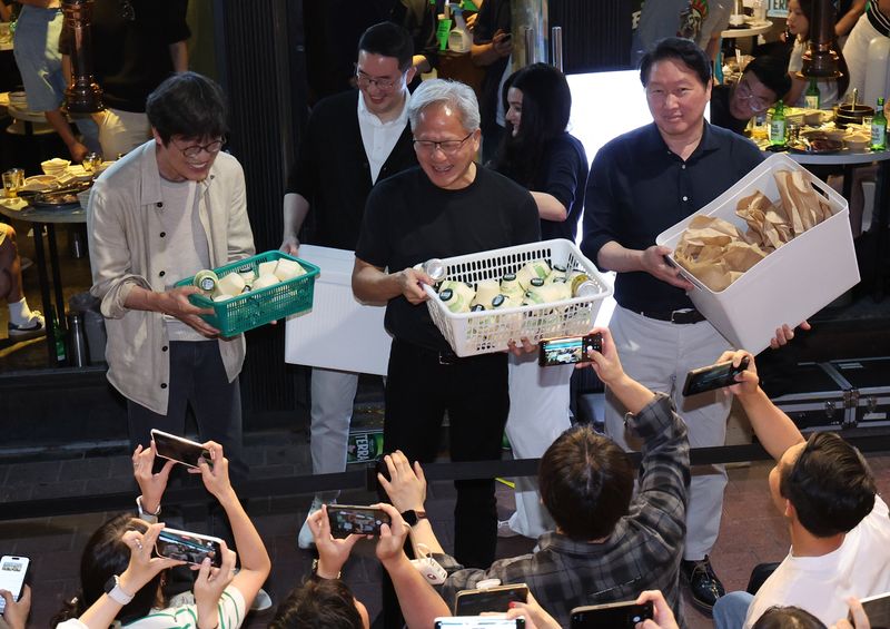 젠슨 황 엔비디아 최고경영자(CEO)가 5일 서울 마포구 홍대 인근의 한 고깃집에서 최태원 SK그룹 회장과 구광모 LG그룹 회장, 이해진 네이버 의장과 이른바 '삼소(삼겹살·소주) 회동' 도중 시민들에게 간식을 나눠주고 있다. 뉴시스
