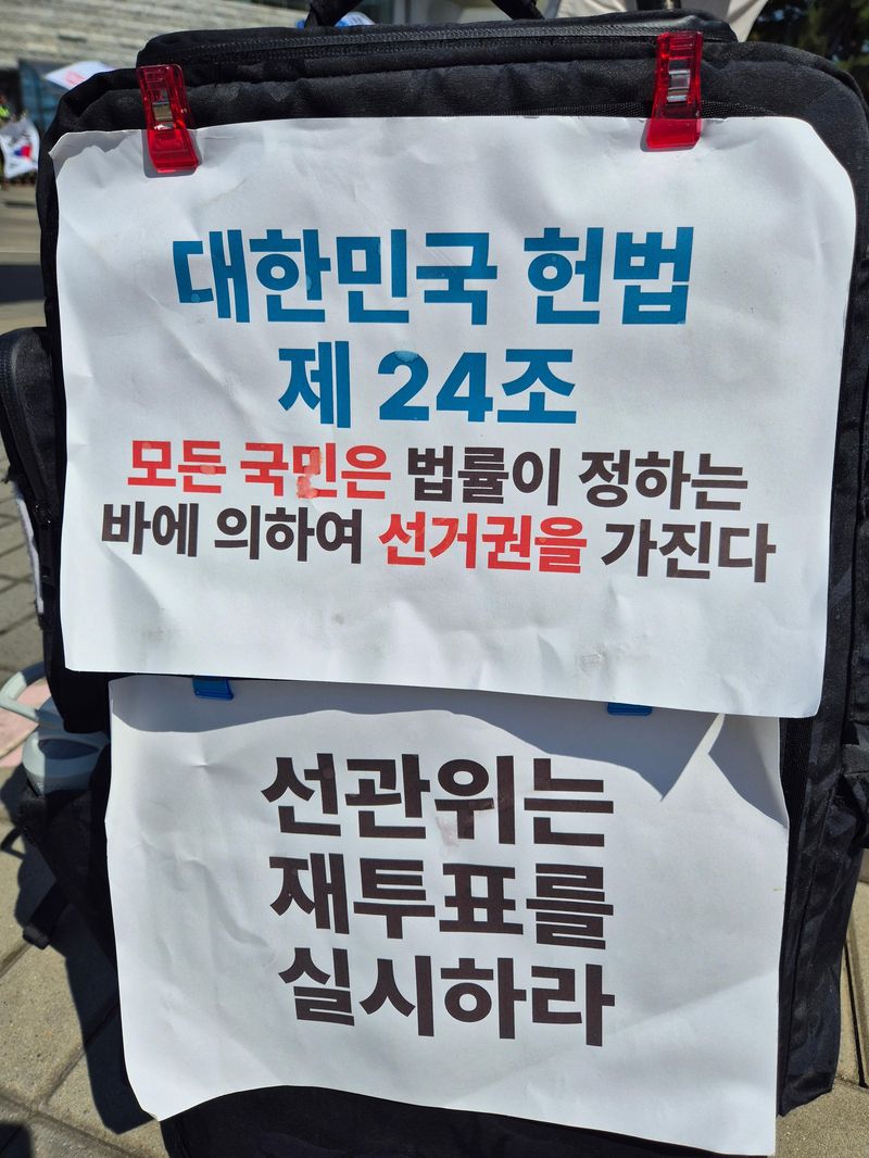 재투표를 촉구하는 문구가 붙어 있는 유권자의 가방. 사진=김예지 기자