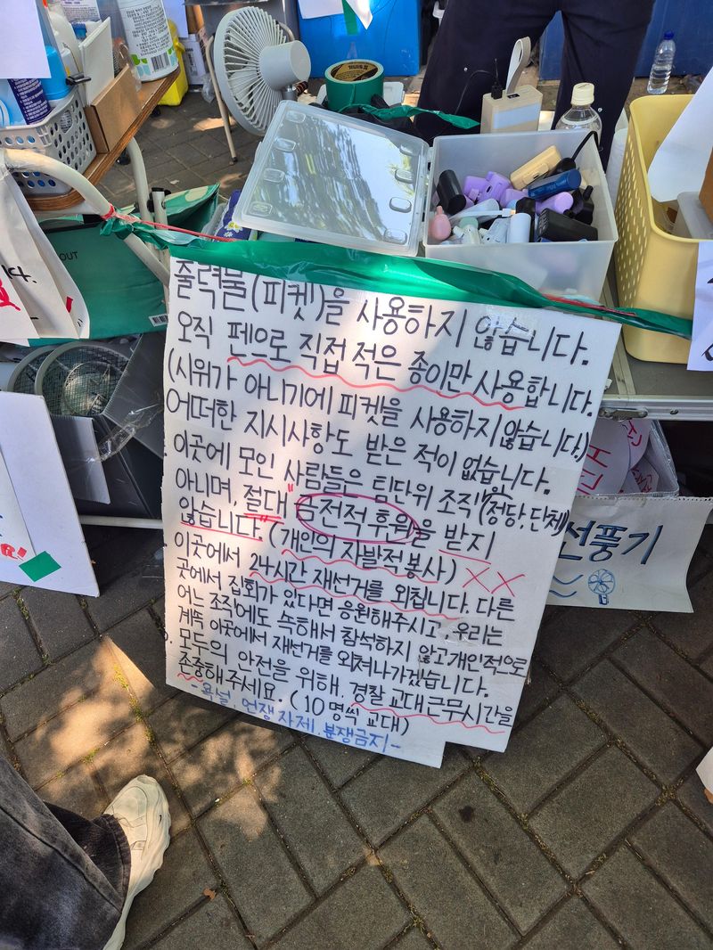현장에서 자원봉사를 이어가는 시민들. 피켓에는 평화 집회를 요청하는 문구가 쓰여 있다. 사진=김예지 기자