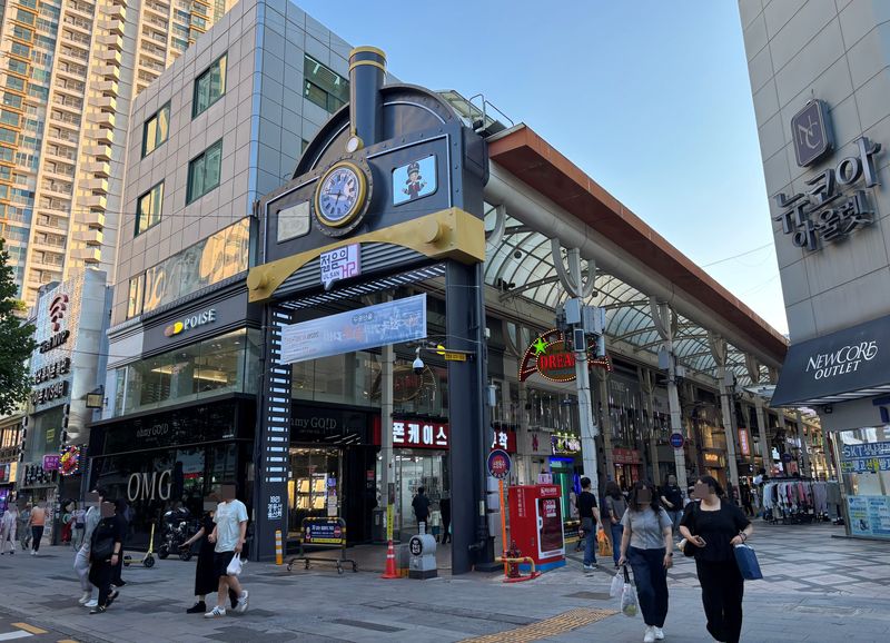 울산시민들이 지난 13일 오후 울산 시계탑 부근 증기 기관차 모양의 쇼핑거리에서 나와 울산 중구 옥교통 중앙전통시장으로 향하고 있다. 기관차 모양의 입구 오른쪽 아래 경동선 울산역 기념석이 세워져있다. 사진=최수상 기자