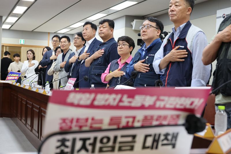 18일 정부세종청사 최저임금위원회에서 열린 제7차 전원회의에서 근로자·사용자·공익 위원들이 국기에 경례하고 있다. 연합뉴스