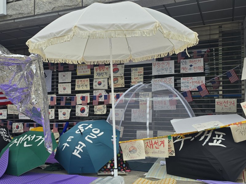 6·3 지방선거 투표용지 부족 사태로 인한 '개표소 봉쇄 시위'가 계속되고 있는 19일 서울 송파구 올림픽공원 핸드볼경기장 출입문 앞에서 참가자들이 물품을 배치해 놨다. 사진=서지윤 기자