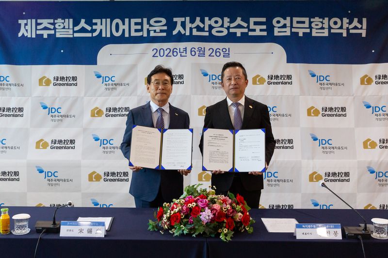 송석언 JDC 이사장과 동건봉 녹지제주헬스케어타운유한회사 사장이 지난 26일 제주첨단과학기술단지 내 JDC 본사에서 체결한 ‘제주헬스케어타운 자산양수도 업무협약서’를 들어 보이고 있다. /사진=JDC 제공