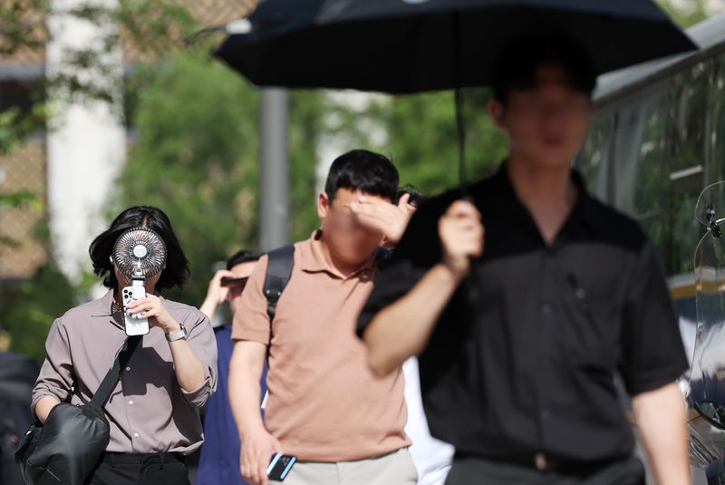 폭염속에서 서울 종로구 거리에서 시민이 선풍기와 양산 등으로 더위를 식히며 이동하고 있다. 뉴시스