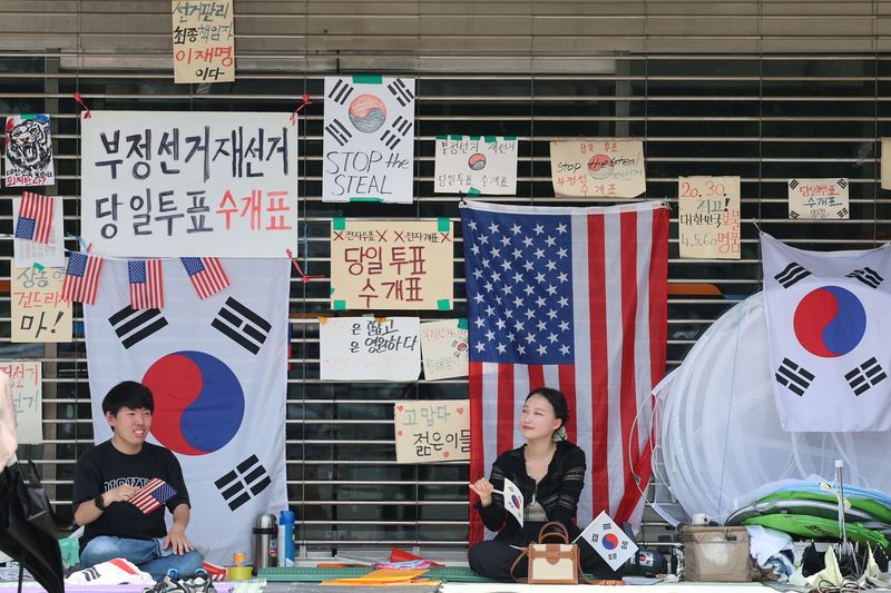 투표용지 부족 사태에 항의하며 개표소 봉쇄 시위가 25일째 이어지고 있는 29일 오후 서울 송파구 올림픽공원 핸드볼경기장 앞에서 시위대들이 문 앞을 지키며 부채를 흔들고 있다. 사진은 기사 내용과 무관함. 뉴시스화상