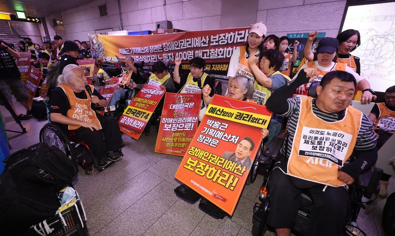 박경석 전국장애인차별철폐연대(전장연) 상임대표를 비롯한 회원들이 지난 7월 2일 오전 서울 중구 1호선 시청역에서 '69차 출근길 지하철 탑니다' 시위에서 구호를 외치고 있다. 뉴시스