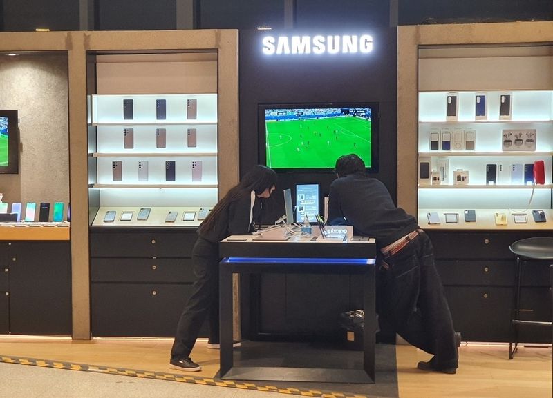 심각한 얼굴로 경기를 보고 있는 매장 직원 (출처=연합뉴스)