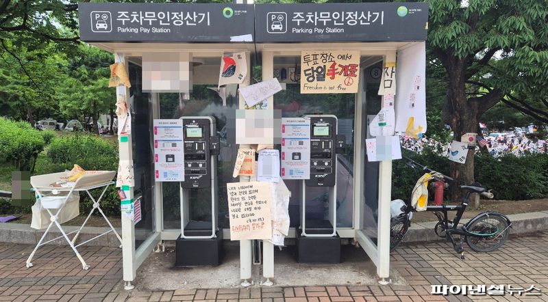 올림픽공원 주차무인정산기 주변에 재선거와 당일 수개표를 요구하는 문구가 붙어 있다. 사진=한승곤 기자