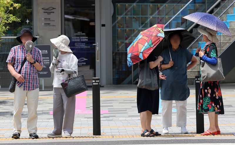 [서울=뉴시스] 이영환 기자 = 폭염이 이어지고 있는 12일 오후 서울 중구 세종대로에서 시민들이 신호를 기다리고 있다. 2026.07.12. 20hwan@newsis.com