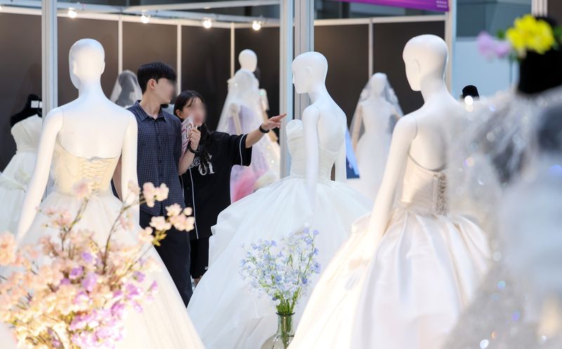 지난해 7월 서울 강남구 삼성동 코엑스에서 열린 2025 추계 웨덱스 웨딩 박람회에서 예비 부부들이 전시된 드레스를 살펴보고 있다. (사진은 기사 내용과 무관함) ⓒ 뉴스1 김성진 기자