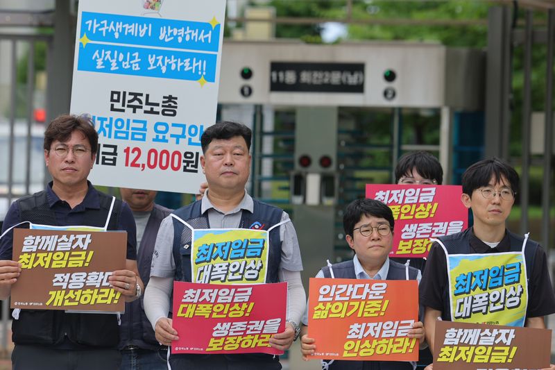 최저임금위원회 제14차 전원회의가 열리는 14일 한국노동조합총연맹(한국노총)과 전국민주노동조합총연맹(민주노총) 조합원들이 정부세종청사 최저임금위원회 앞에서 기자회견을 열고 있다. 연합뉴스