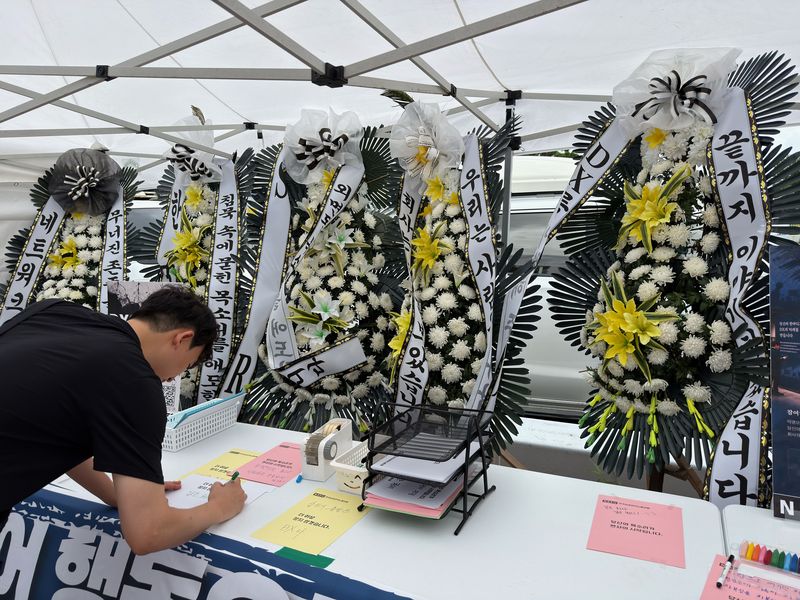 14일 경기 수원 삼성전자 수원사업장 중앙문 앞에 차려진 합동분향소에서 한 삼성전자 직원이 게시판에 글을 남기고 있다. 사진=정원일 기자