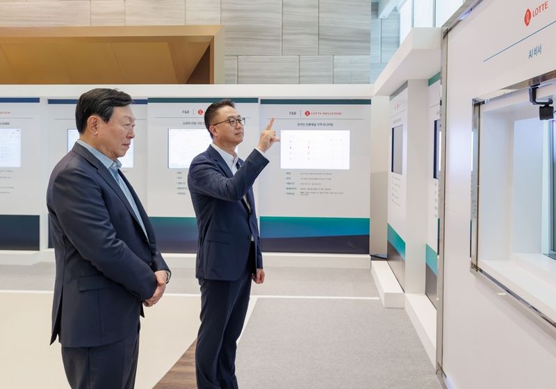 15일 서울 롯데월드타워에서 2026년 하반기 VCM이 진행되기 앞서 신동빈 롯데 회장(왼쪽)이 황민재 롯데지주 경영혁신실장(오른쪽)으로부터 음성과 모션 인식 기반 'AI 비서'에 대한 설명을 듣고 있다. (롯데 제공)