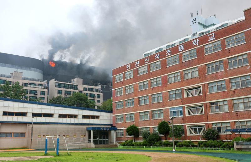 인천 쿠팡 물류센터 화재가 사흘째 이어지고 있는 20일 임시 휴교한 인천 서해구 신석초등학교 옆으로 화염과 연기가 치솟고 있는 물류센터가 보인다. 연합뉴스