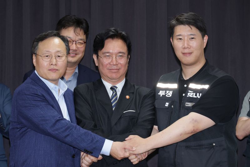 20일 경기도 수원시 장안구 경기고용노동청에서 열린 삼성전자 임금협상을 마친 후 여명구 삼성전자 DS(디바이스솔루션·반도체 사업 담당) 피플팀장과 김영훈 고용노동부 장관, 최승호 삼성그룹 초기업노동조합 삼성전자지부 위원장이 잠정 합의한에 서명한 후 손을 맞잡고 있다. (공동취재) 2026.5.20 ⓒ 뉴스1 김영운 기자