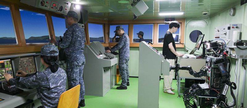 23일 해군교육사령부 조함훈련장에서 해군 최초로 진행된 로봇 승조원 전투실험에서 휴머노이드 로봇 '파이봇(PIBOT)'이 이지스구축함 서애류성룡함(DDG) 소속 함교 당직사관의 조함명령에 따라 타수 업무를 수행하고 있다. 해군 제공