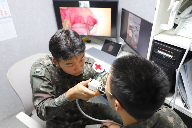 [서울=뉴시스] 20일 '원격진료시스템'을 활용중인 21사단 GOP대대 소속 의무병이 국군의무사령부 의료종합상황센터 군의관(화상)의 지시에 따라 환자의 상태를 확인하고 있다.(사진=육군 제공) 2025.06.20. photo@newsis.com *재판매 및 DB 금지