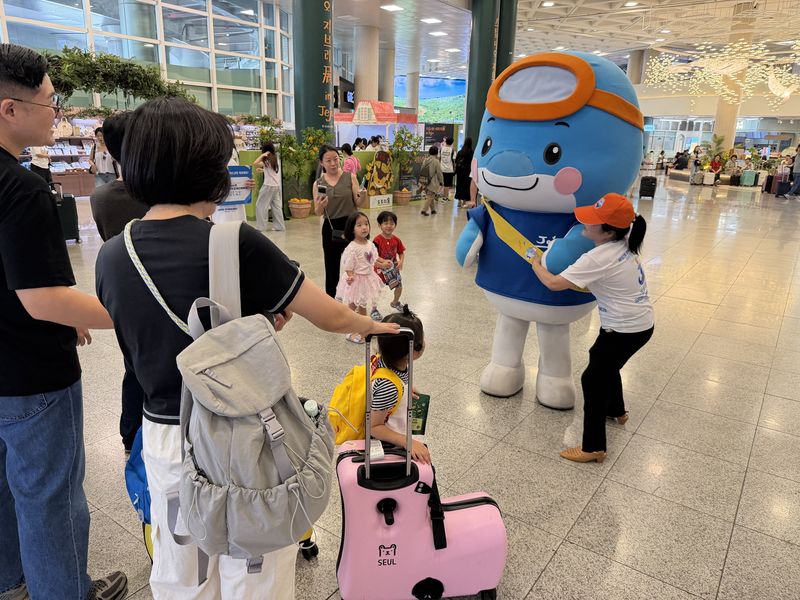 30일 제주국제공항 1층 도착장에서 전국체전 마스코트 ‘끼요’가 관광객 가족과 만나고 있다. 여행가방을 든 어린이와 보호자들이 끼요 앞에서 기념사진을 찍으며 제주에서 열리는 전국장애인체육대회와 전국체육대회 홍보 행사에 참여하고 있다. /사진=제주특별자치도 제공