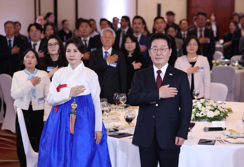 이재명 대통령과 김혜경 여사가 29일(현지시간) 칠레 산티아고 한 호텔에서 열린 동포 만찬간담회에서 국기에 경례하고 있다. 연합뉴스