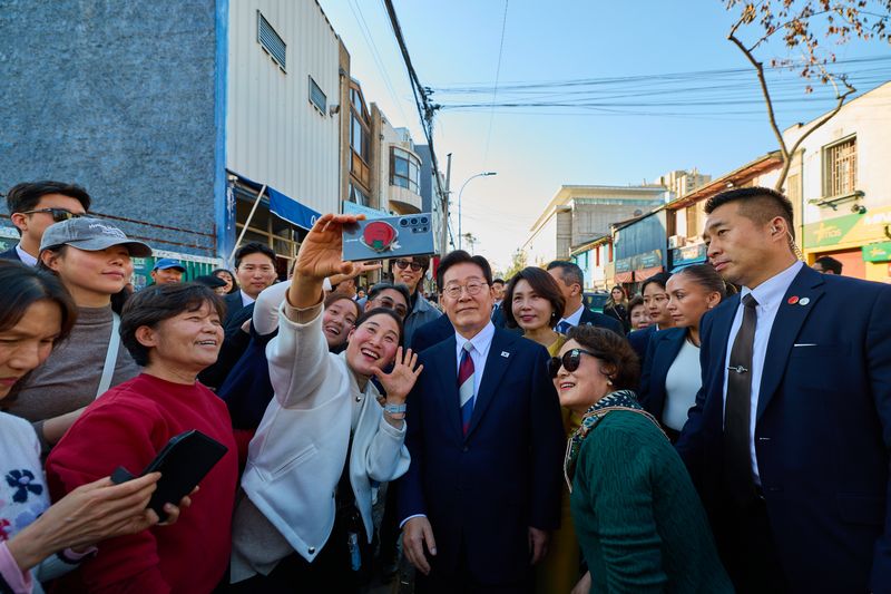 이재명 대통령과 김혜경 여사가 지난 7월30일(현지시간) 칠레 산티아고 한국의 거리를 방문해 시민들과 기념촬영을 하고 있다. 뉴스1