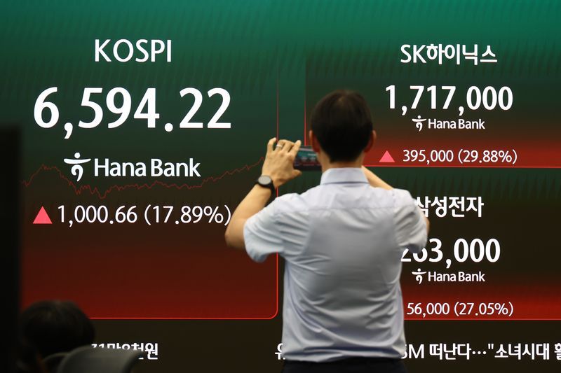 7월 31일 서울 하나은행 딜링룸에서 딜러가 18% 가까이 상승한 코스피를 보며 스마트폰으로 촬영하고 있다./사진=뉴시스