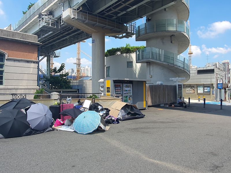 6일 서울 용산구 서울역 2번 출구 인근에서 노숙인들이 우산과 짐으로 임시 공간을 마련하거나 그늘에 누워 폭염을 피하고 있다. 사진=최승한 기자
