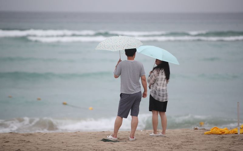 먹구름이 드리운 제주시 함덕해수욕장에서 관광객들이 우산을 쓰고 있다. 제주지방기상청은 15~16일 제주에 30~80㎜, 산지에는 150㎜ 이상의 비가 내리고 해상에는 최고 3m의 물결이 일 것으로 예보했다. /사진=뉴스1
