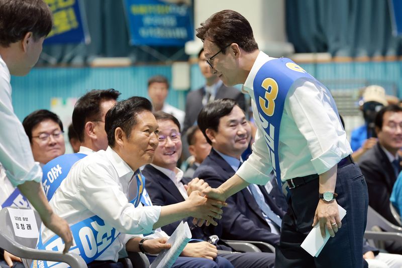 더불어민주당 김민석 당 대표 후보가 9일 강원도 횡성국민체육센터에서 열린 민주당 대표·최고위원 후보자 강원 합동연설회에서 정견 발표한 뒤 자리로 돌아가며 정청래 당 대표 후보와 악수하고 있다. 연합뉴스