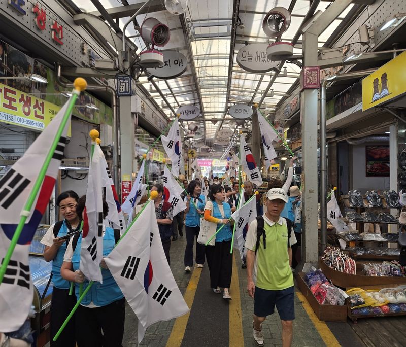부산시재향군인회 임직원들이 수영구 팔도시장 상인들에게 태극기를 나눠주며 광복 81주년 기념 나라사랑 홍보 캠페인을 펼치고 있다. 부산시재향군인회 제공